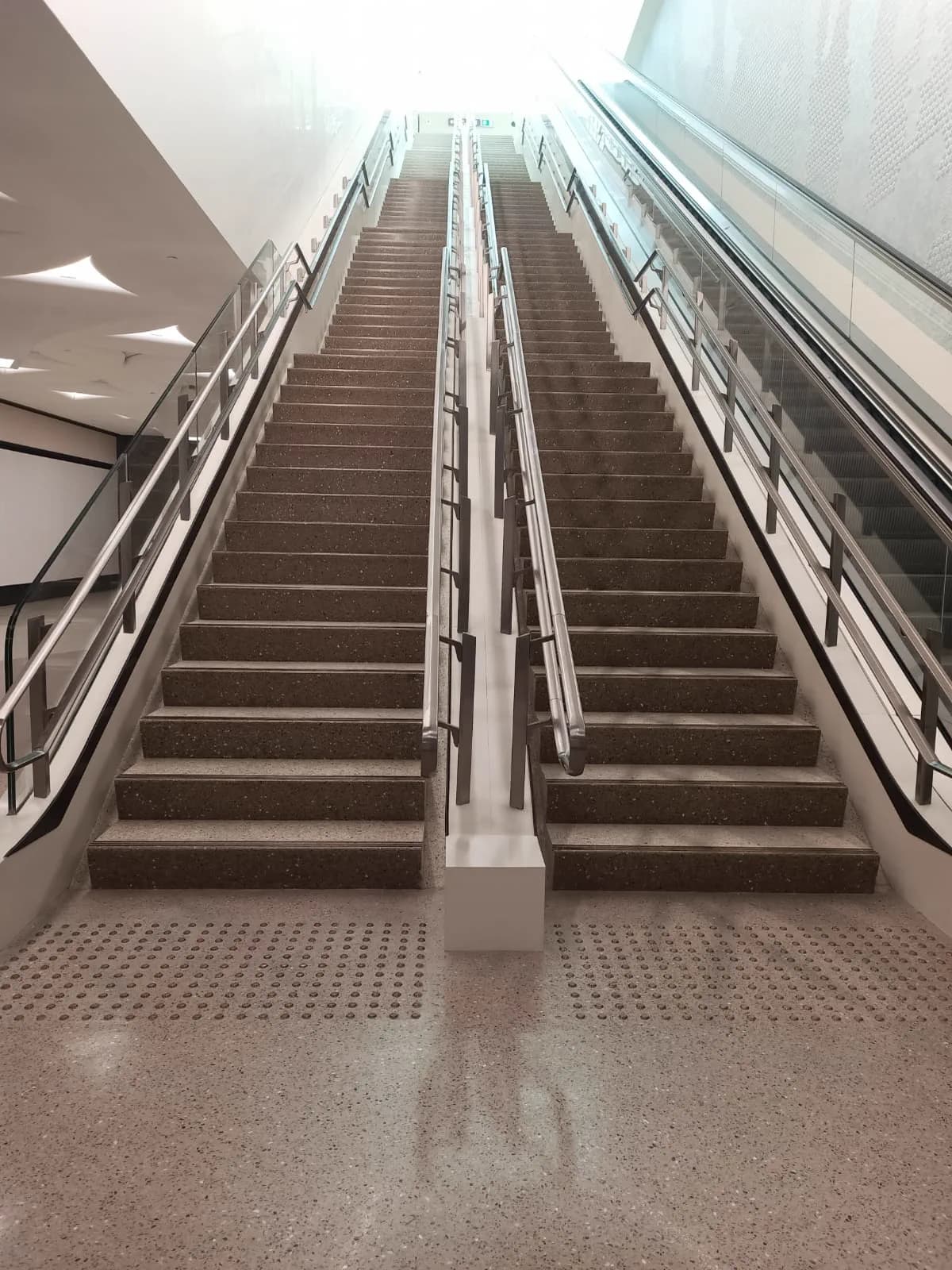 Metro station staircase in Doha with contrasting stair nosings and a tactile warning surface at the base of the flight