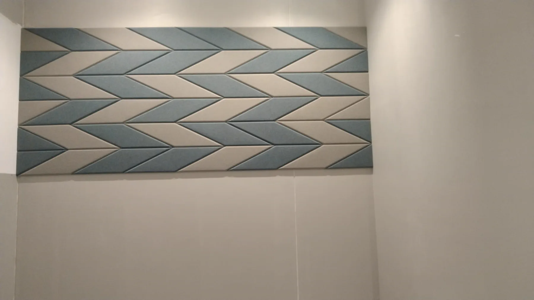 Detail of a KTS fabric-wrapped acoustic panel in a teal and cream chevron pattern, manufactured in Doha, Qatar
