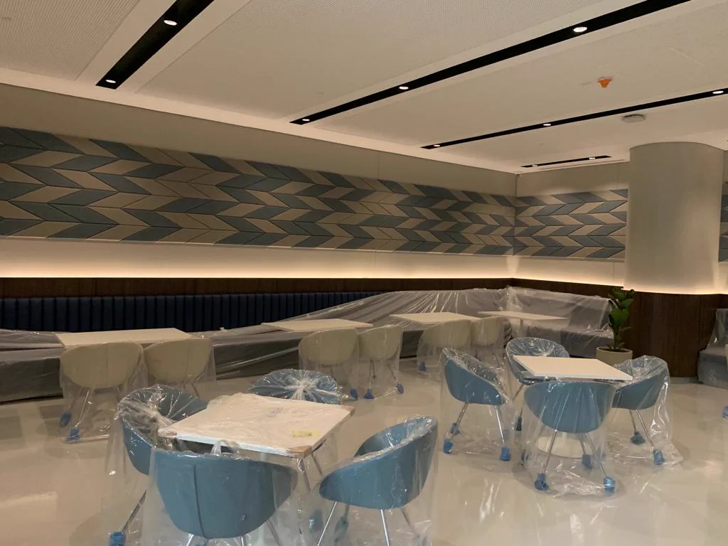 Blue and beige chevron fabric-wrapped acoustic panels running the length of a library café wall in Doha, Qatar, above banquette seating