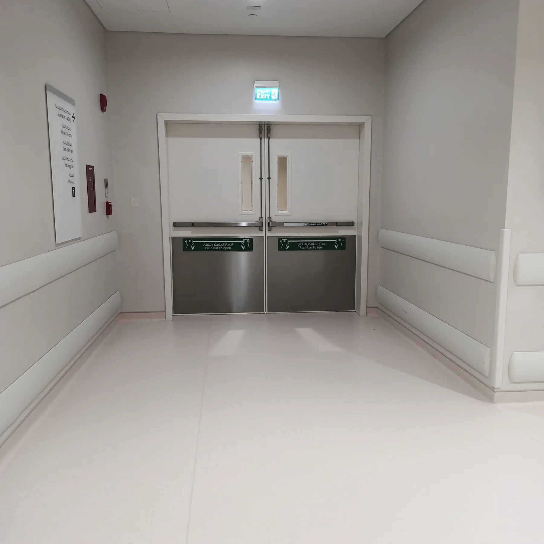 Hospital corridor lobby in Doha with impact wall protection rails, stainless steel double doors and seamless vinyl flooring
