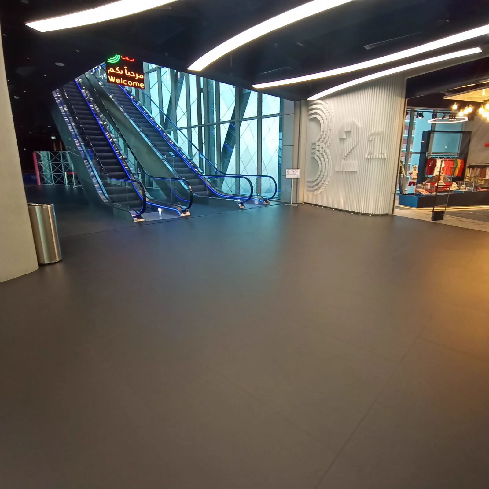 Museum atrium in Doha with grey seamless rubber flooring leading to blue-lit escalators and a ribbed feature wall